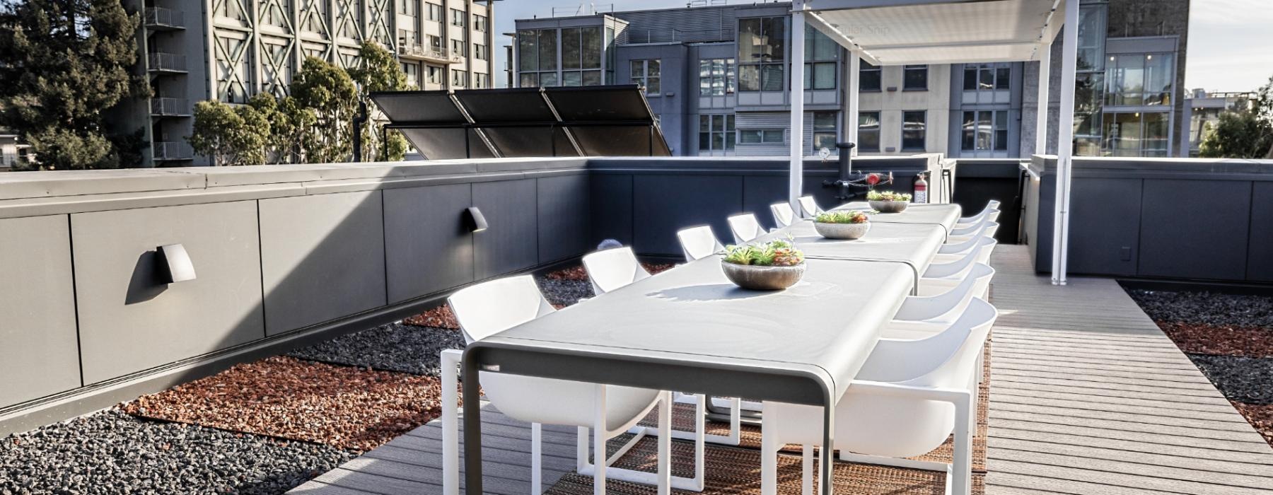 a deck with a table and chairs on it and buildings in the background